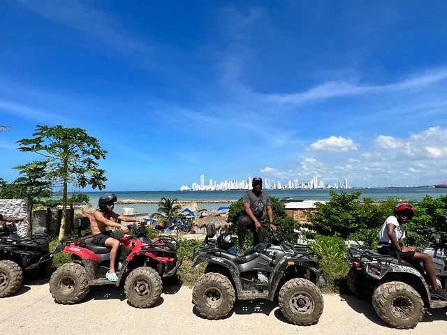 Personen auf geparkten ATVs am Wasser, mit einer Skyline der Stadt im Hintergrund.