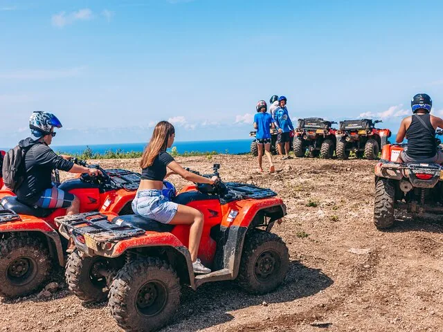 Gruppe von Touristen auf roten ATVs auf einem unbefestigten Weg nahe der Küste.