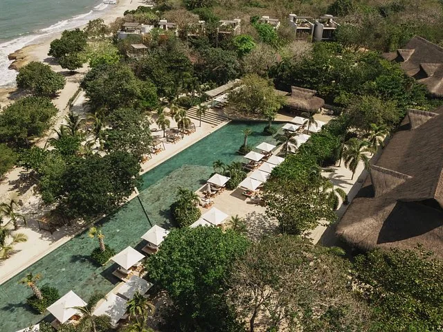 Aerial view of a resort with a long swimming pool and lounge chairs