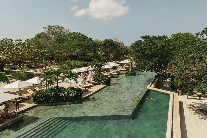 Ein großer Pool einer Ferienanlage, gesäumt von Liegestühlen und Sonnenschirmen