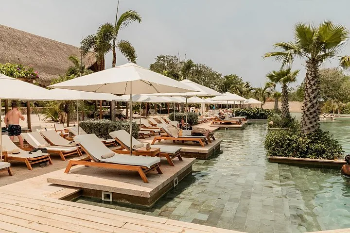Liegestühle mit Sonnenschirmen neben einem Swimmingpool in einem Resort